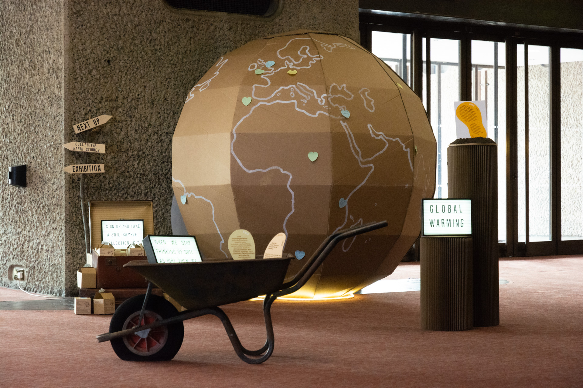 A wheelbarrow in front of a giant cardboard globe